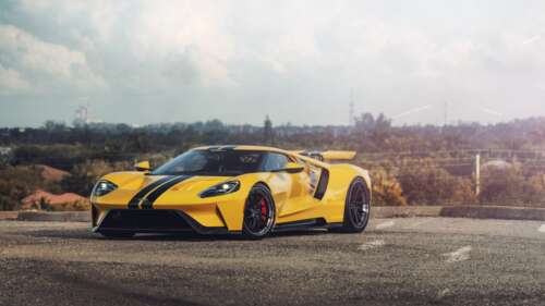 A sleek and powerful yellow Ford GT supercar showcasing its aerodynamic design and... 8K wallpaper for pc download