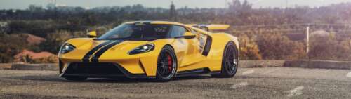 A sleek and powerful yellow Ford GT supercar showcasing its aerodynamic design and... Dual UHD free wallpaper