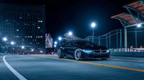A sleek BMW i8 supercar parked on a dark street at night, featuring glowing headlights... 8K free wallpaper for computer