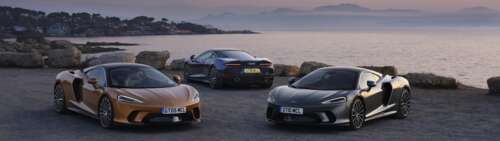 Two McLaren GT supercars parked together, one in metallic silver and one in bright... Dual UHD wallpaper