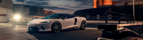 A sleek white McLaren GT supercar featuring modern aerodynamic design and luxury...