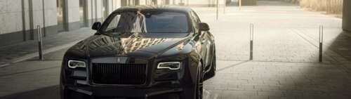 A premium black Rolls-Royce Wraith luxury vehicle featuring a deep glossy finish. Dual UHD computer backgrounds