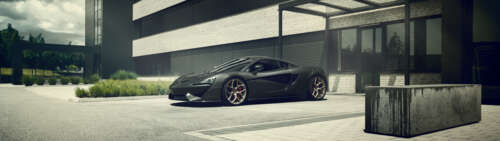 A glossy black McLaren 570S supercar showcasing its sleek aerodynamic design. wallpaper
