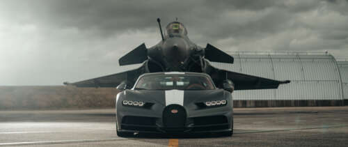 A black Bugatti Chiron supercar parked next to a stealth jet fighter in a dark, atmospheric... UWUHD wallpaper