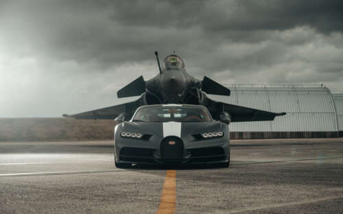 A black Bugatti Chiron supercar parked next to a stealth jet fighter in a dark, atmospheric... 7680x4800 desktop wallpaper