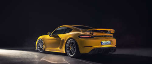 A vibrant yellow Porsche 718 Cayman sports car. UWUHD desktop wallpaper
