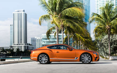 A sleek orange Bentley Continental GT luxury car.