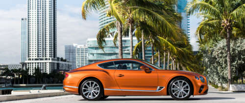 A sleek orange Bentley Continental GT luxury car.