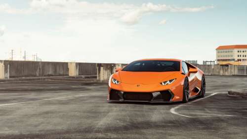 A sleek and polished bright orange Lamborghini Huracan supercar showcasing its aerodynamic... 4K (Ultra HD) wallpaper for pc download