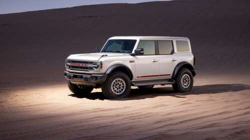 A futuristic 2026 Ford Bronco driving through vast, golden desert sand dunes. computer backgrounds