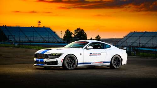 A high-performance Ford Mustang Dark Horse race car driving on a track during a vibrant... free hd wallpapers