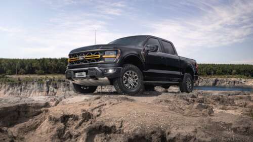 A fleet of modern, high-detail off-road trucks traversing a dusty, rocky desert landscape. wallpaper