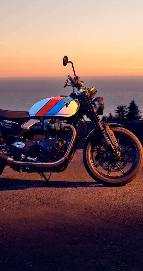 A modern 2025 motorcycle parked against a vibrant sunset sky with warm orange and... Sharp Aquos C10 hd background