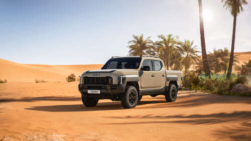 A futuristic 2025 off-road truck traversing a rugged, dusty desert landscape with... wallpaper
