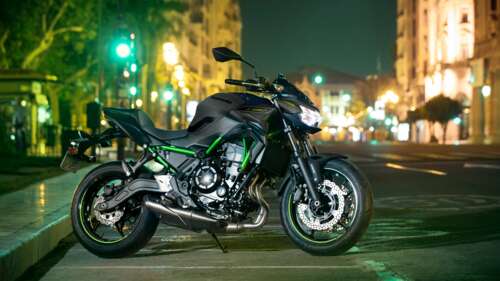 A high-detail close-up of a 2023 Modenas motorcycle reflecting colorful city lights... free wallpaper