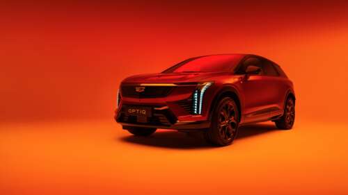 The 2025 Cadillac Optiq electric SUV presented against a bold orange background. wallpaper