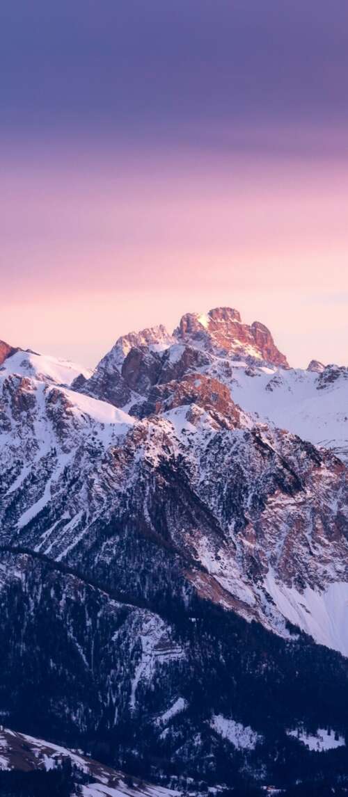 Majestic snow-covered mountains under a colorful gradient sunset sky during golden... wallpaper
