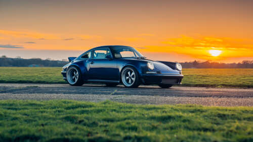 A vintage Porsche 911 parked against a beautiful sunset with orange and pink clouds... wallpaper