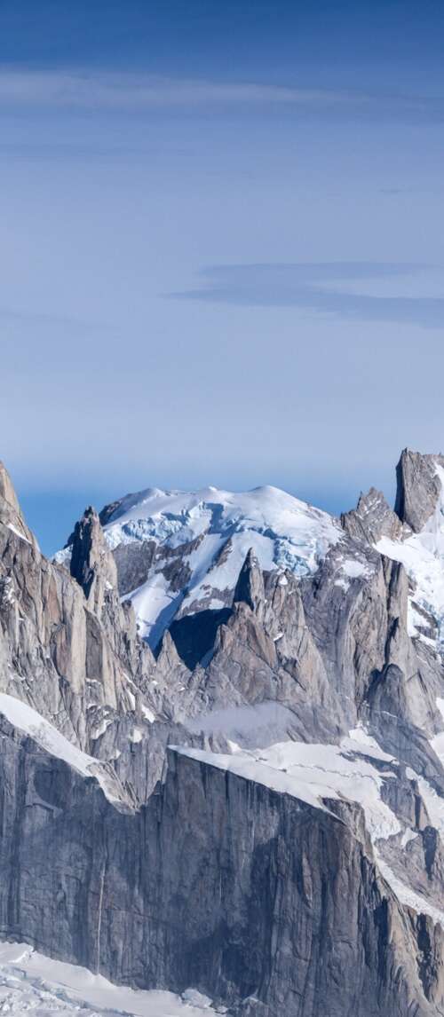 Snow-covered peaks of Cerro Torre and Fitz Roy mountains in Patagonia under a bright... free wallpaper