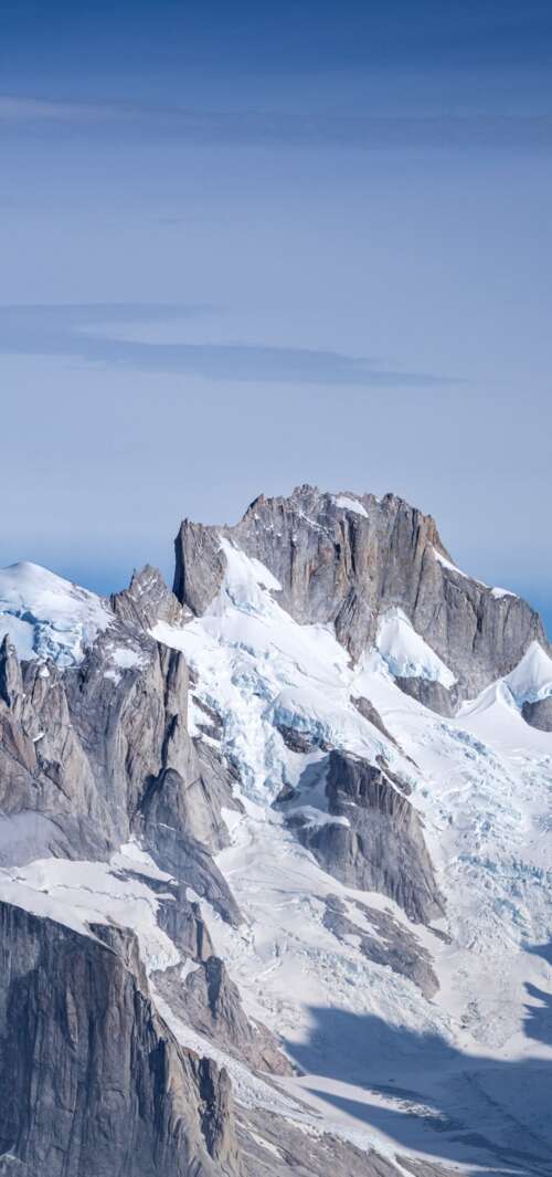 Snow-covered peaks of Cerro Torre and Fitz Roy mountains in Patagonia under a clear... wallpaper