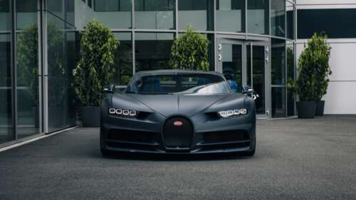 A matte black Bugatti Chiron Sport luxury hypercar parked on a city street. wallpaper