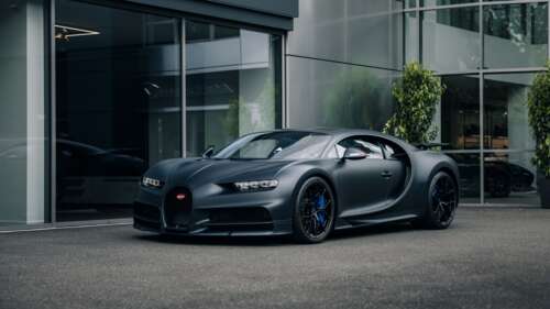 A matte black Bugatti Chiron Sport parked on a city street under urban lighting. wallpaper