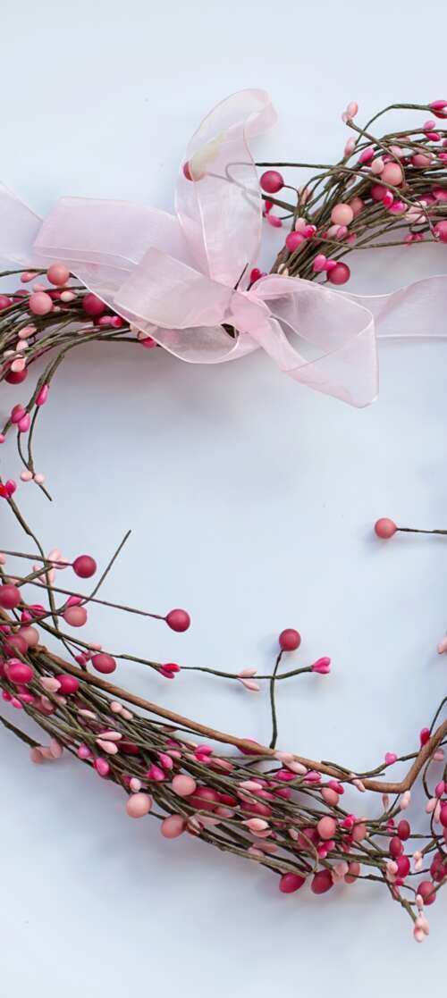 A heart-shaped wreath featuring pink spring flowers and green leaves on a white background. wallpaper