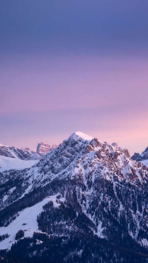 A wide panoramic view of snow-covered mountain peaks under a colorful gradient sky... wallpaper download