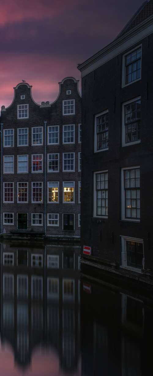 A scenic view of Amsterdam's canals at sunset with illuminated historic buildings... wallpapers for android