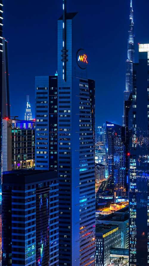 A panoramic night view of the Dubai skyline with illuminated skyscrapers and bright... wallpaper
