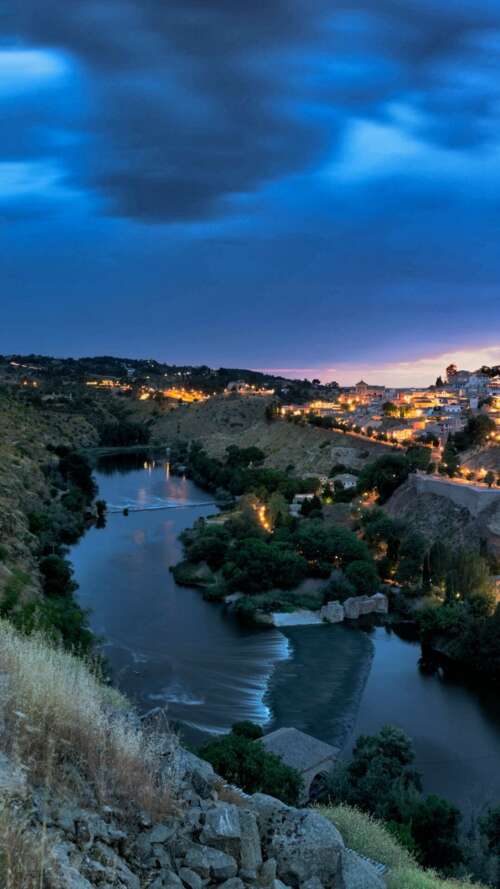 A panoramic night view of a Spanish city skyline featuring glowing city lights and... download free wallpaper for phone