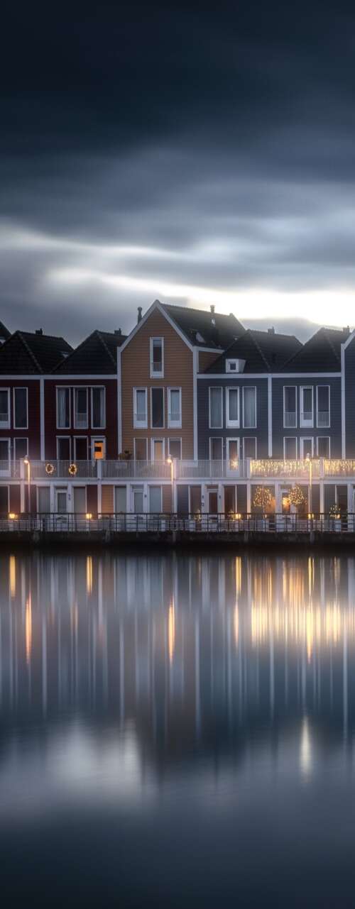 A scenic view of a wooden house by a lake in the Netherlands under a colorful evening... wallpaper