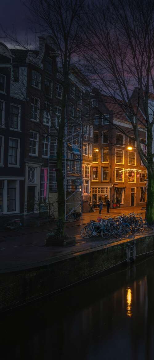A scenic nighttime view of Amsterdam's canals with sunset reflections on the water... wallpaper