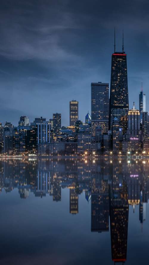 A dramatic nighttime view of the Chicago, Illinois skyline featuring illuminated... wallpaper
