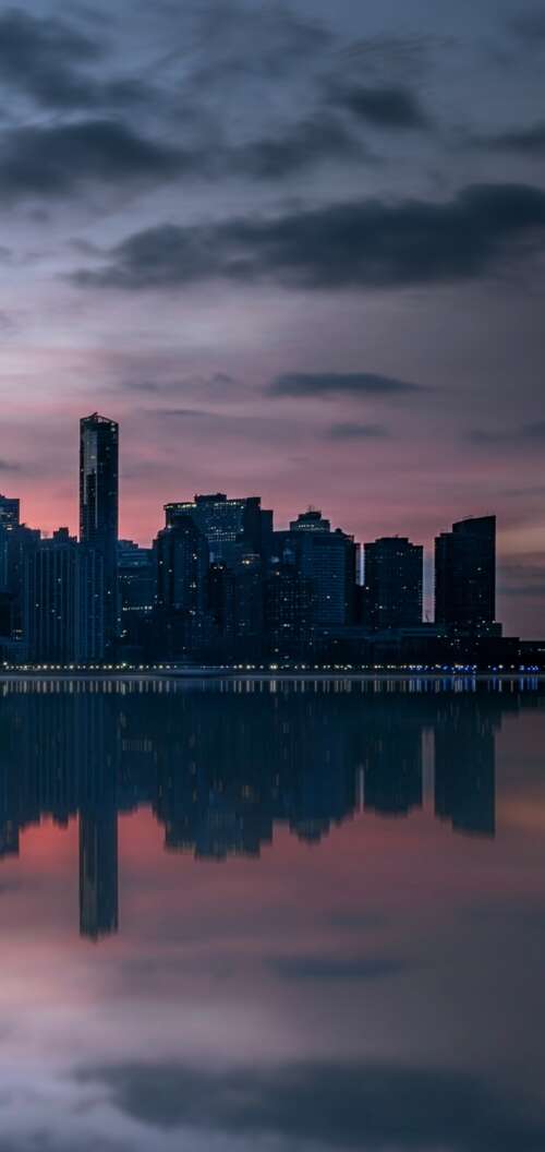 Manhattan skyline and skyscrapers reflecting in the Hudson River under an evening... free wallpaper