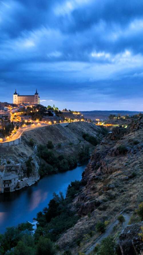 A wide panoramic view of a Spanish city at night featuring bright city lights and... mobile wallpaper