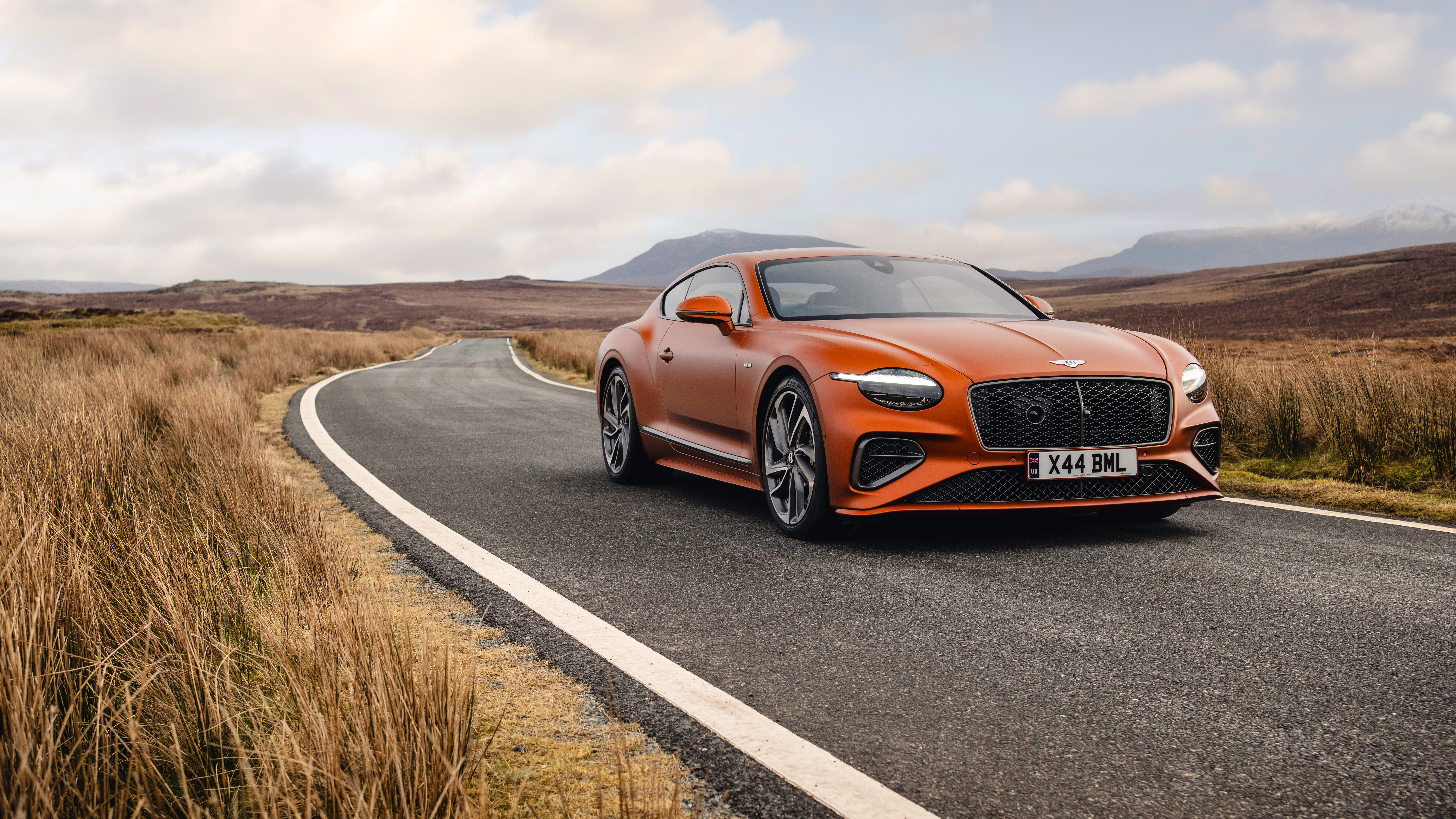 A vibrant orange Bentley Continental GT Speed showcasing its luxurious design and powerful stance.