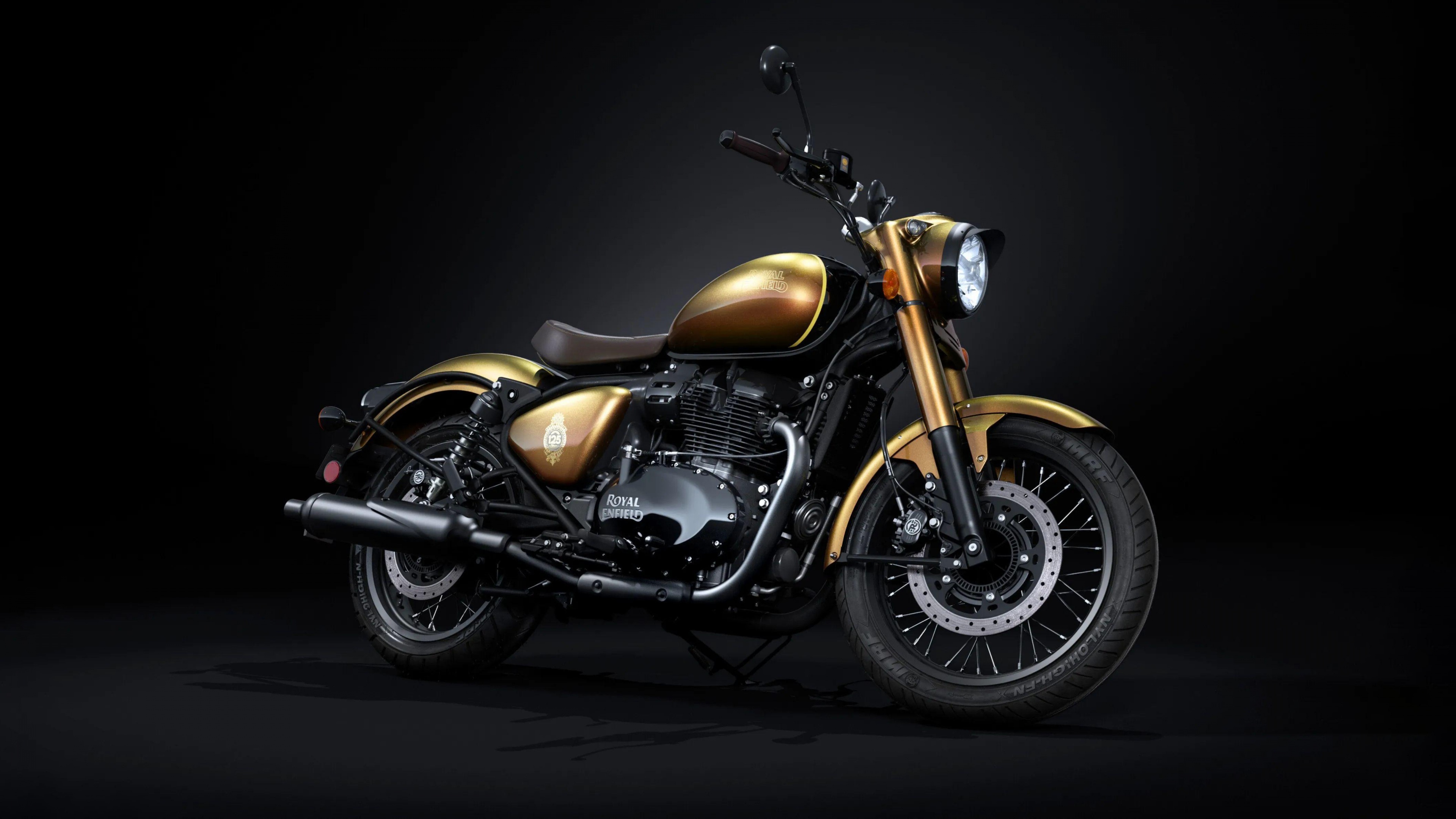 A close-up shot of the 2025 Anniversary Edition motorcycle on display at the EICMA show, featuring dramatic lighting and a dark, moody atmosphere.