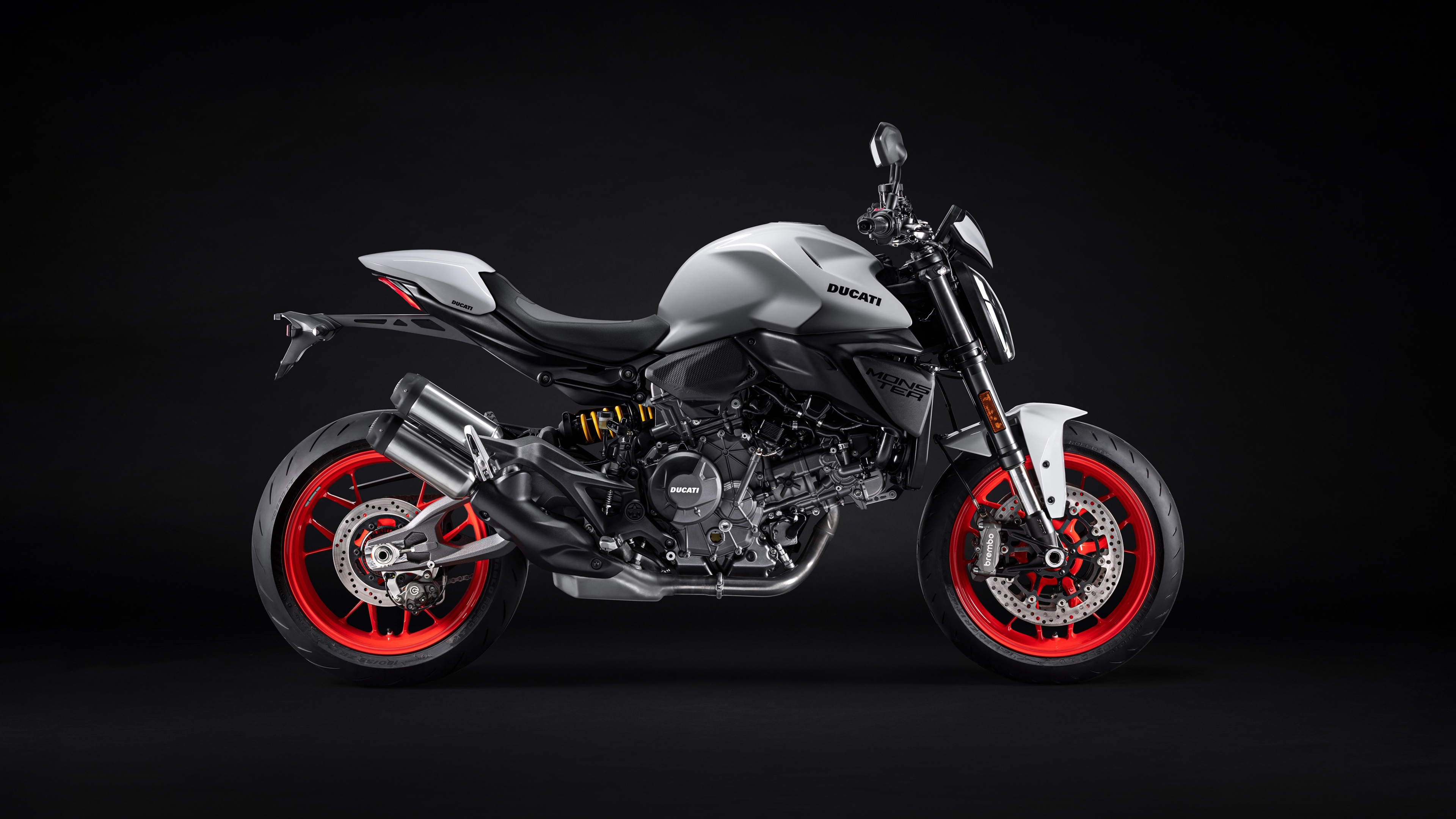 A 2026 Ducati Monster V2 sports motorcycle captured in a dark, high-contrast setting.