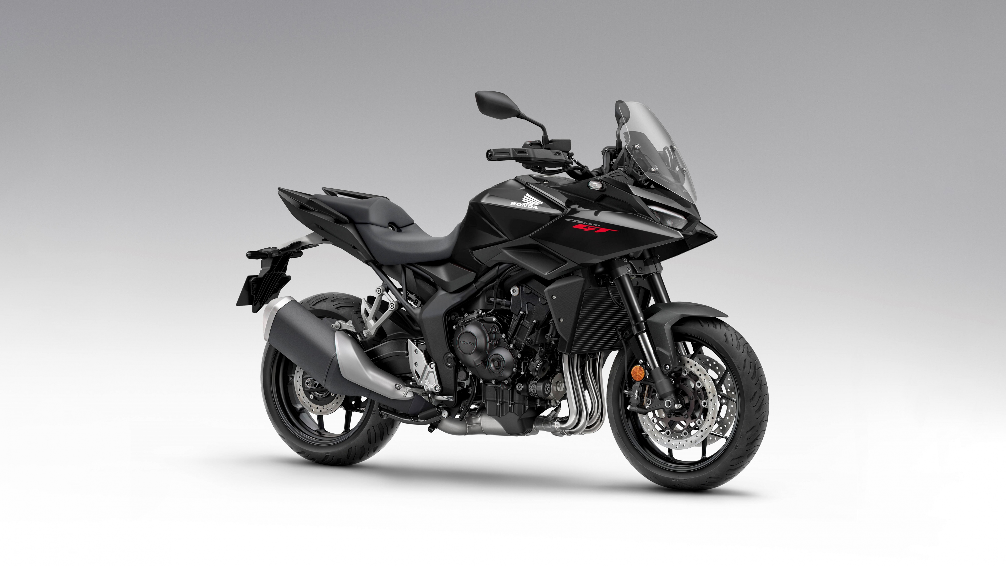 A sleek black 2026 Honda CB1000GT touring motorcycle with aerodynamic fairings and a matte black finish.
