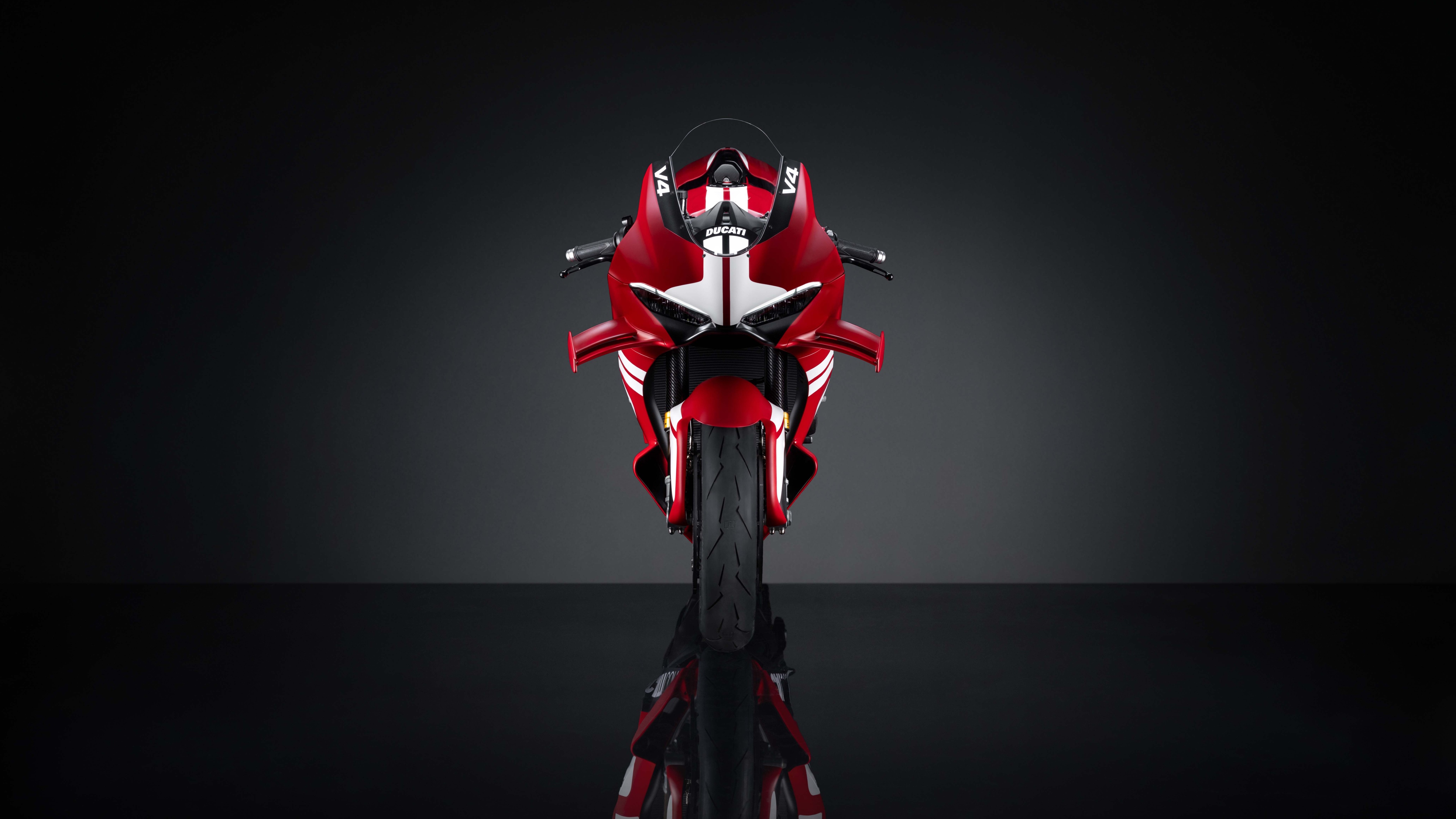 Una vista dettagliata e ad alta risoluzione della futuristica moto sportiva Ducati Superleggera V4 Centenario, ripresa in un ambiente di studio con illuminazione soffusa.