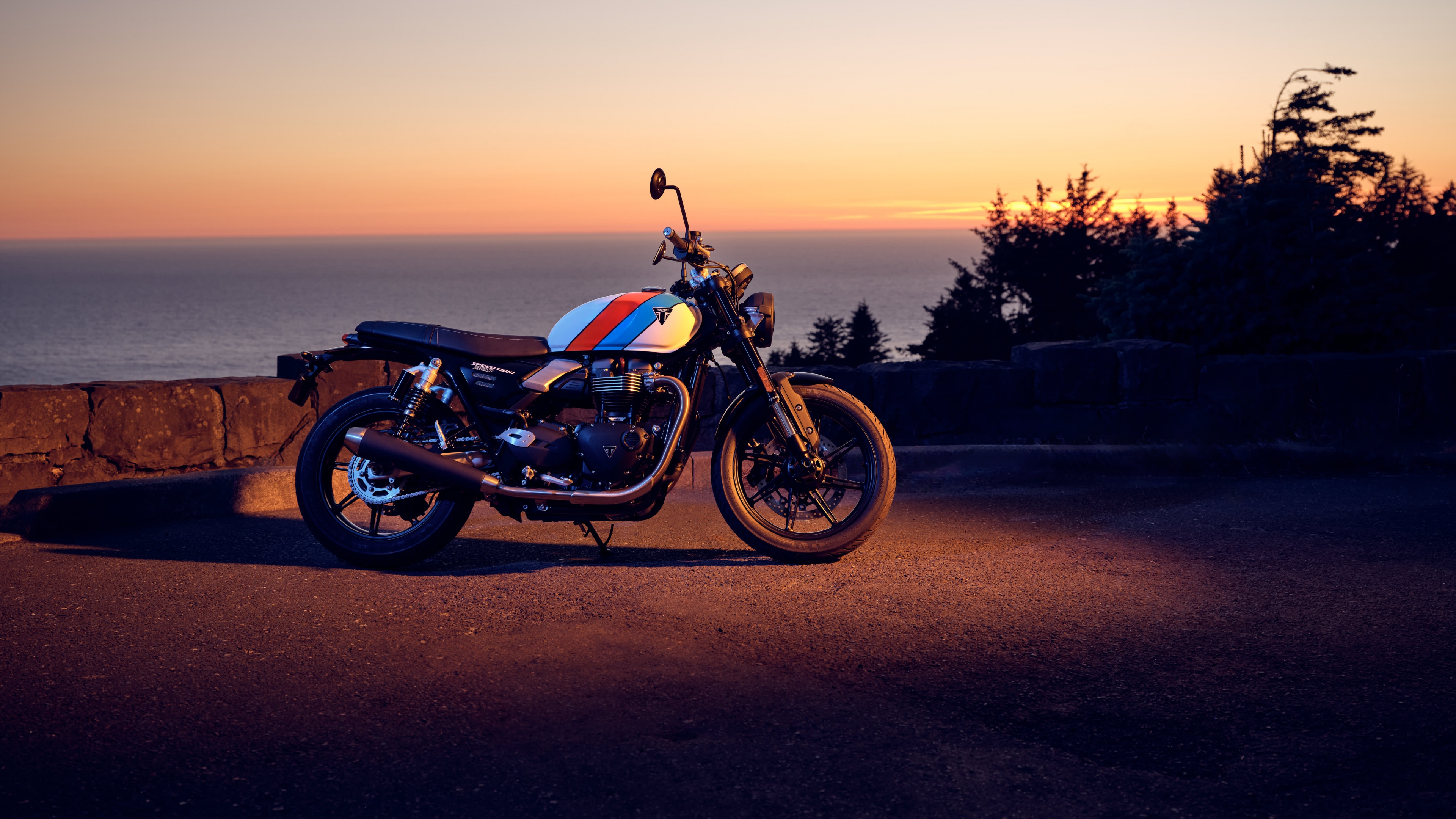 A sleek motorcycle silhouetted against a vibrant orange and gold sunset sky during the golden hour.