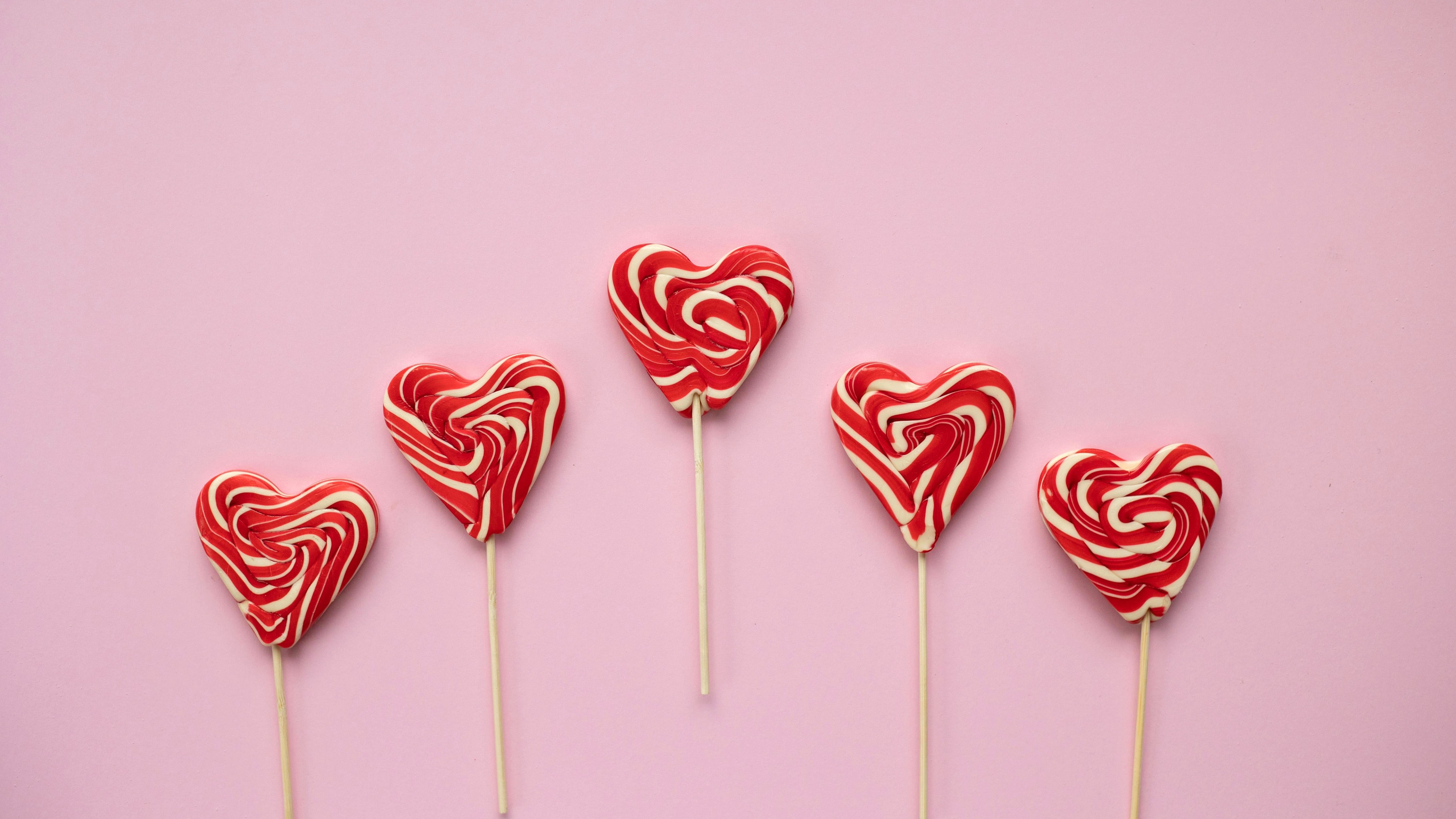 An assortment of pastel pink candies and red heart-shaped lollipops arranged aesthetically.