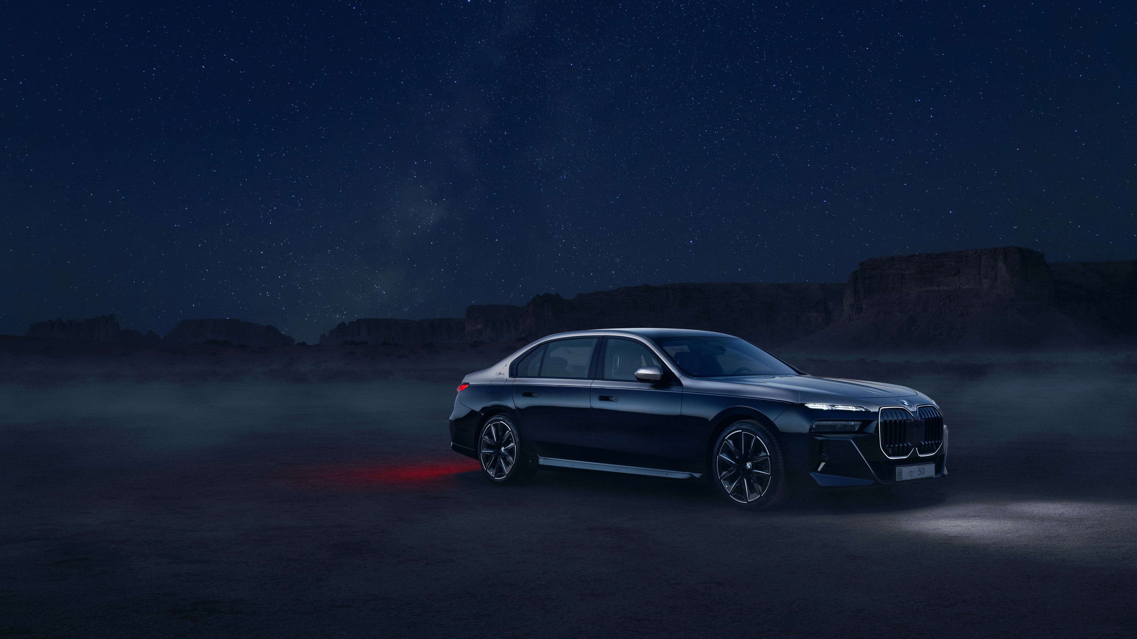 A luxurious 2025 BMW 760i xDrive sedan illuminated under night lights, showcasing its modern automotive design.