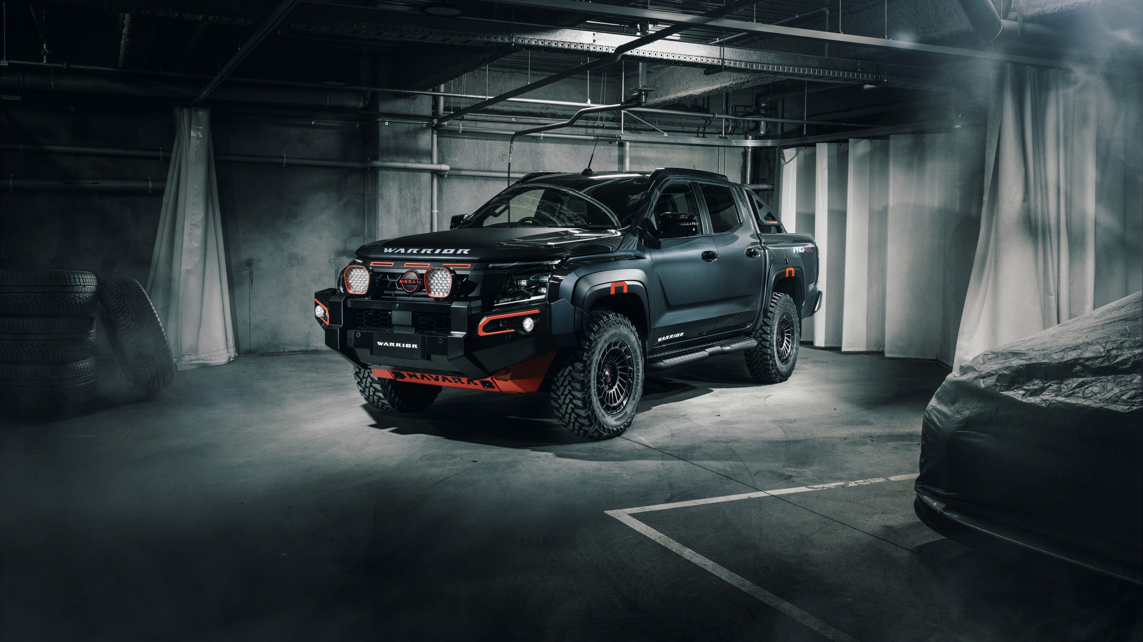 A matte black rugged 2025 off-road pickup truck parked in a concrete parking garage.