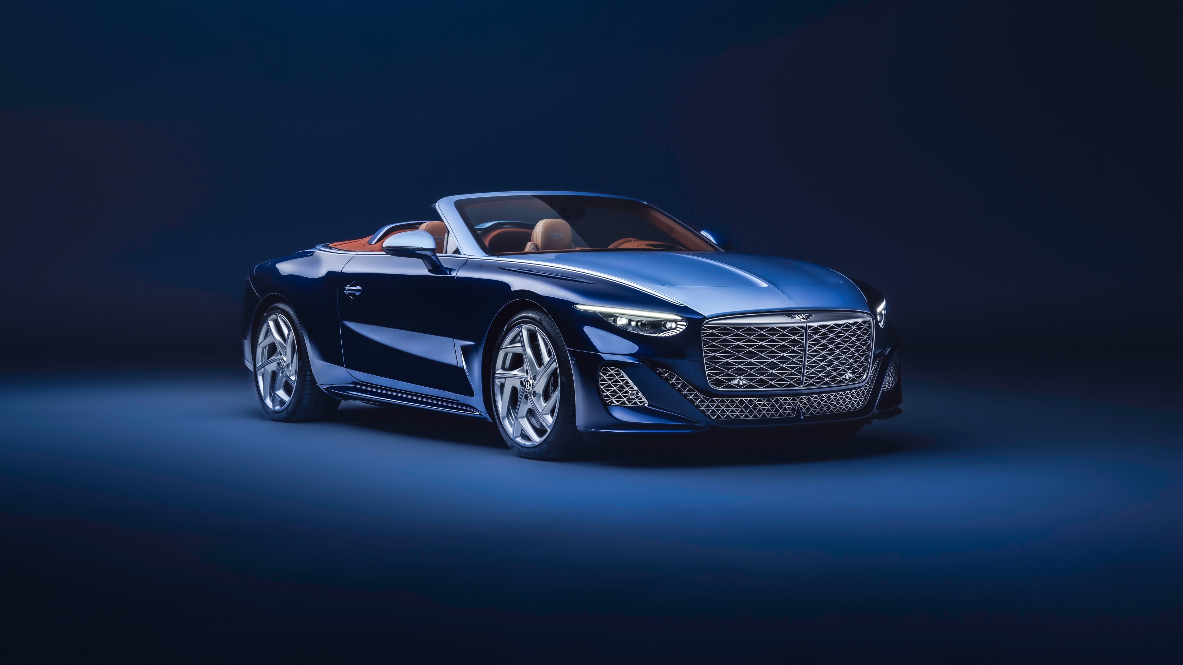 A luxurious blue Bentley Mulliner Batur Convertible positioned against a matching blue studio backdrop.
