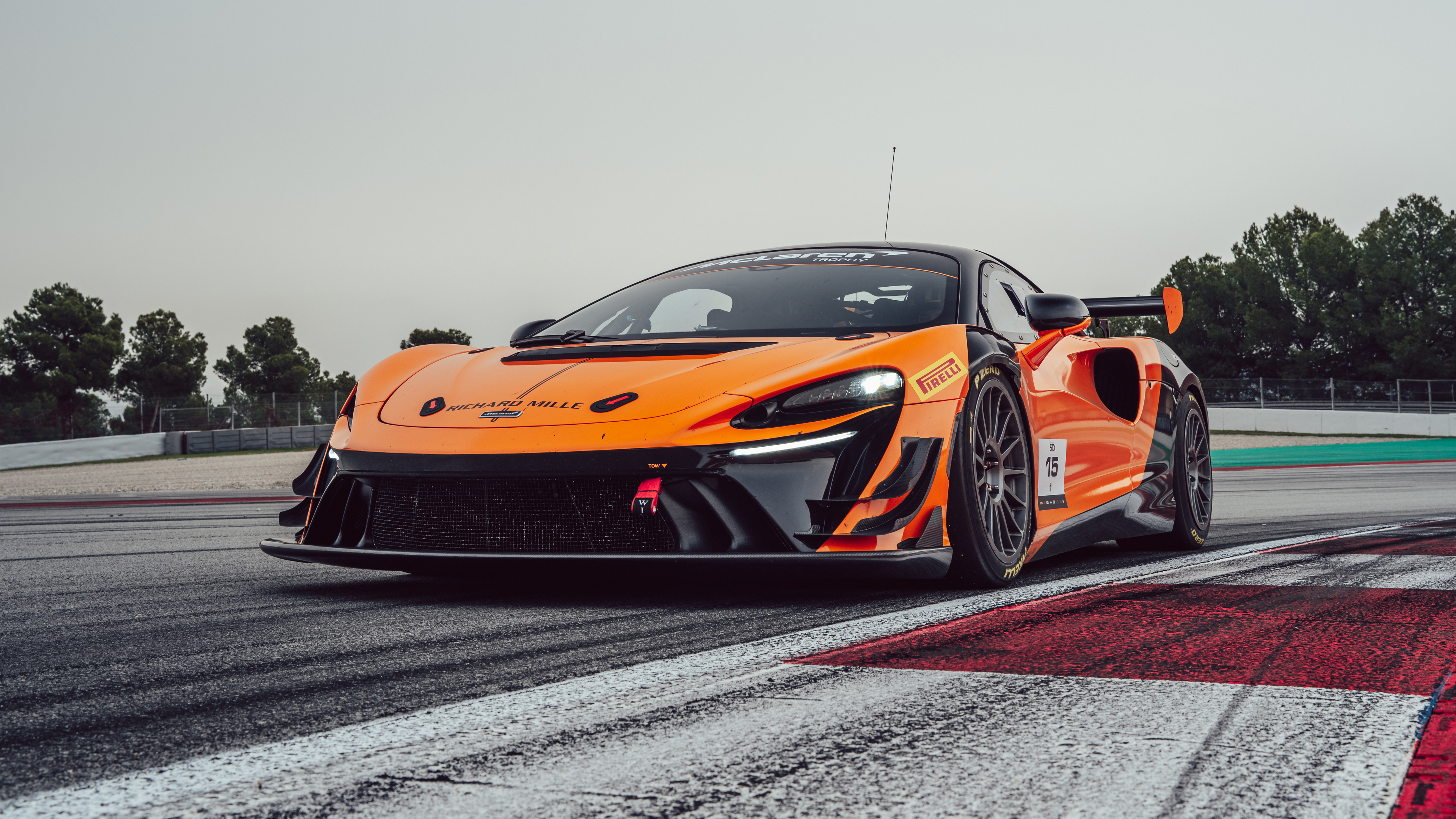 A futuristic McLaren Artura race car driving on a smooth asphalt track