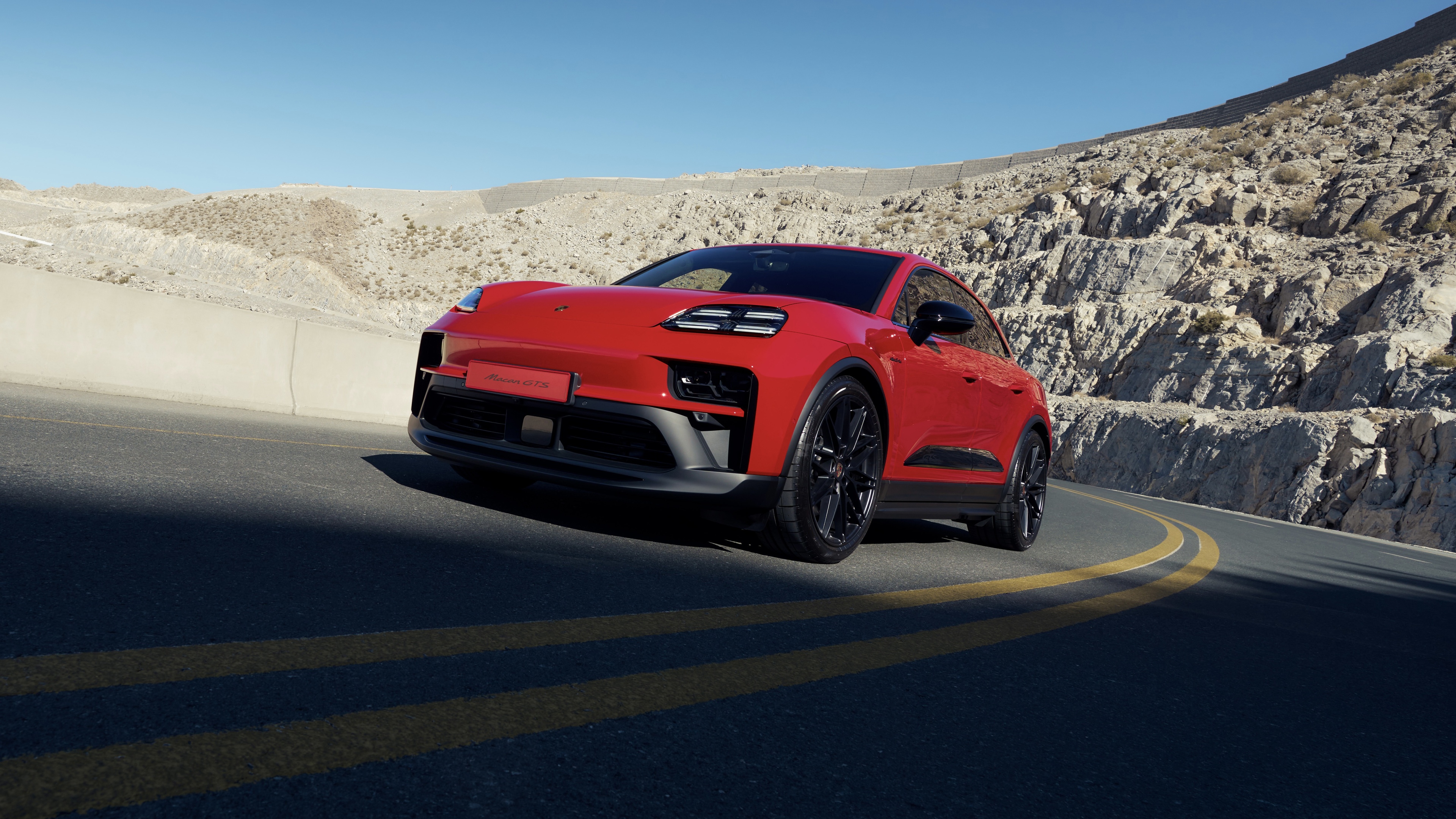 A sleek and vibrant red 2026 Porsche Macan GTS luxury SUV featuring aerodynamic contours and a sporty design.