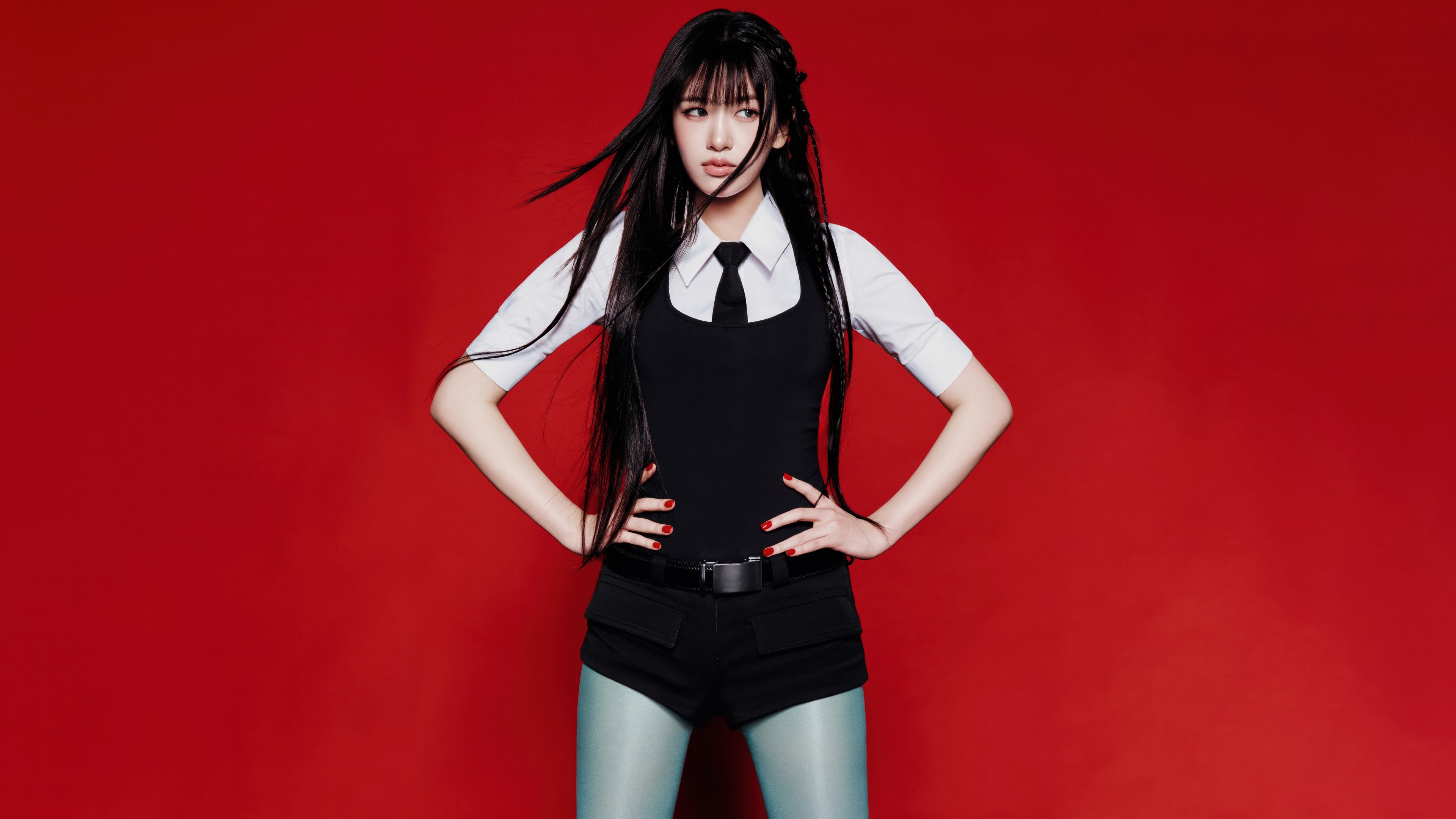 An Yujin from the K-pop group IVE wearing an elegant black dress against a bold red background