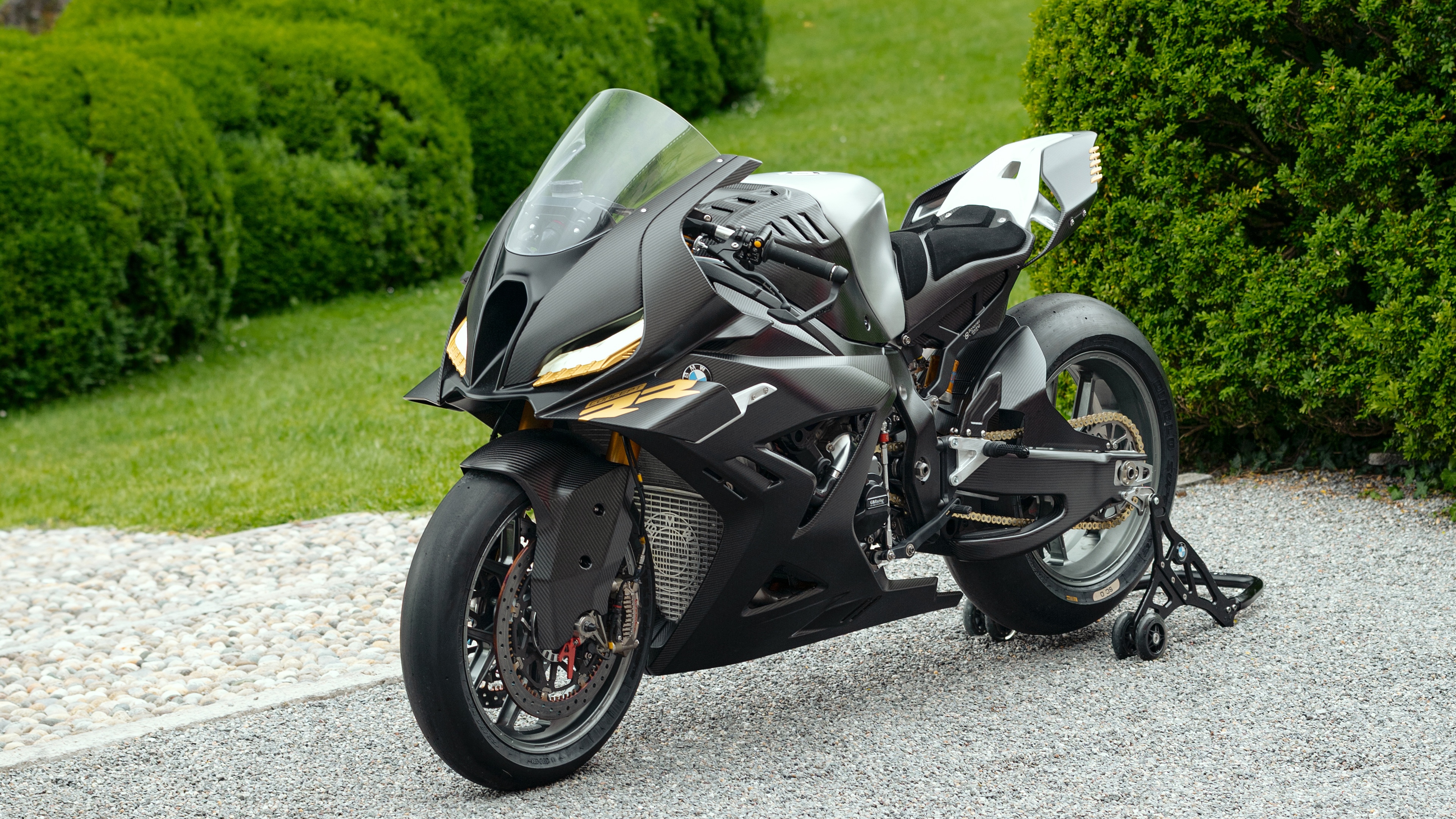 A futuristic BMW Motorrad Concept RR sports motorcycle with advanced aerodynamic features parked in a scenic outdoor environment.